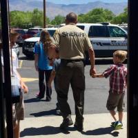 Photo showing a police officer holding hands with a kid after shopping